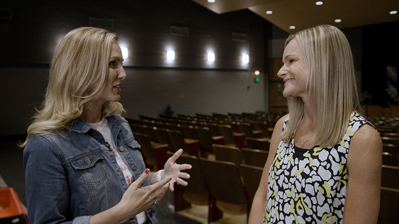 Two women, Lauren and Erin, talk in a school building.